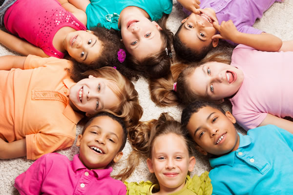 Un grupo de ocho niños sonríen formando una estrella en el suelo. :: FOTOLIA